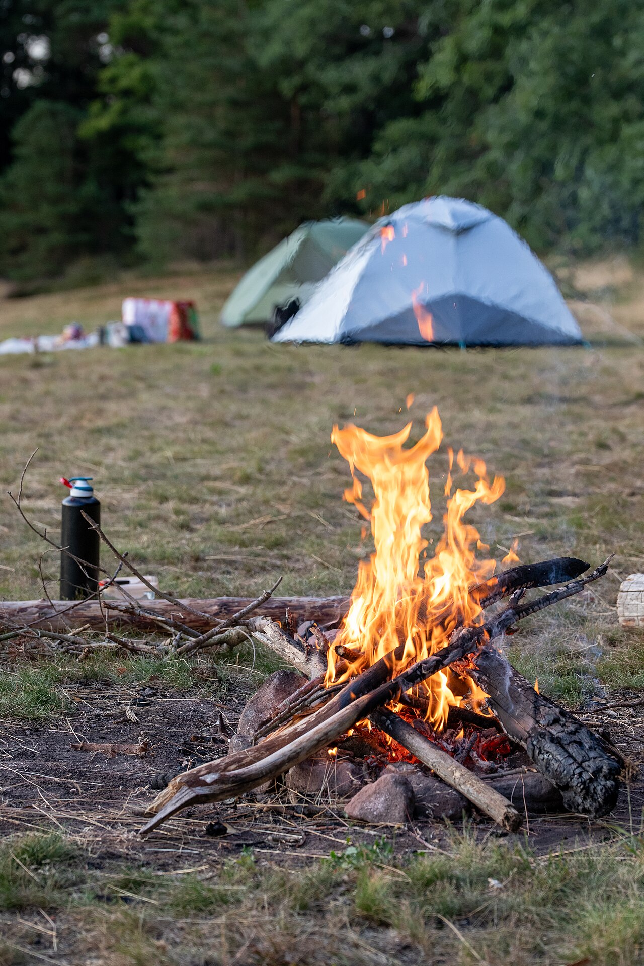 Feu de camp devant deux tentes, le soir